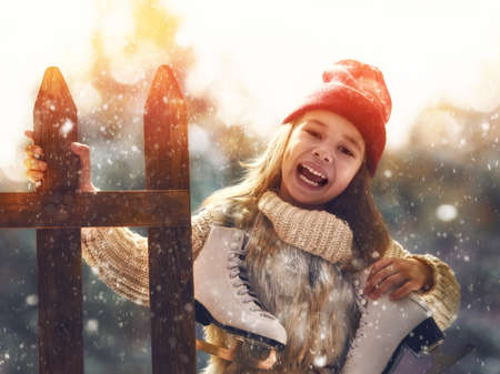 Happy child playing on a winter walk in nature. Cute little kid girl is going skate outdoors.の写真素材