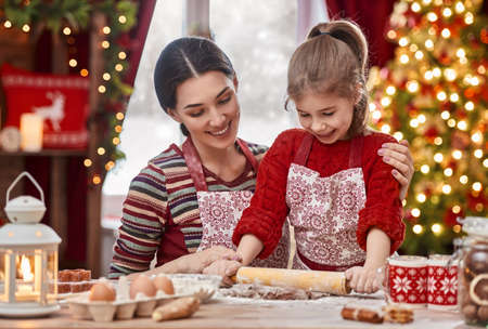 Merry Christmas and Happy Holidays. Family preparation holiday food. Mother and daughter cooking Christmas cookies.の写真素材