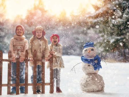 Cute children girls and boy playing on a winter walk in nature. Happy kids outdoors.の写真素材