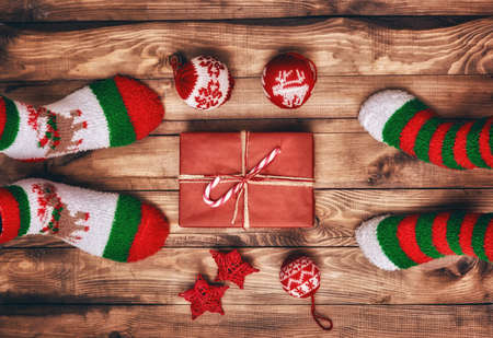 Merry Christmas and Happy Holidays! A parent and child with Xmas gift. Baubles, present, candy and feet in socks with christmas ornaments. Top view. Christmas family traditions.の写真素材