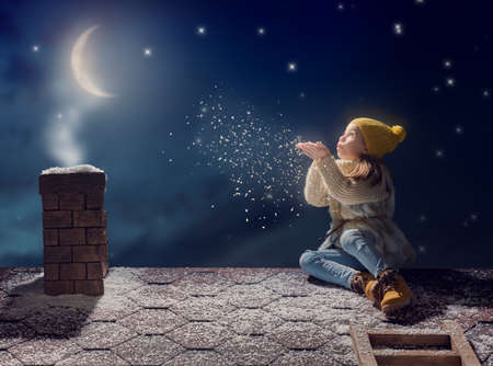 Happy child girl playing on a snowy winter walk. Little girl enjoys the game. Child girl sitting on...
