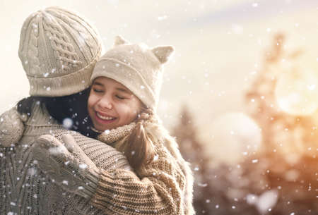 Happy loving family! Mother and child girl having fun, playing and laughing on snowy winter walk in nature. Frost winter season.の写真素材
