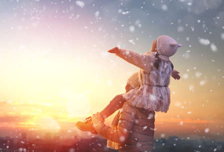 Happy loving family! Mother and child girl having fun, playing and laughing on snowy winter walk in nature. Frost winter season. の写真素材