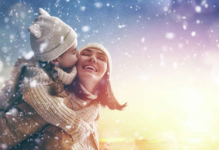 Happy loving family! Mother and child girl having fun, playing and laughing on snowy winter walk in nature. Frost winter season.の写真素材