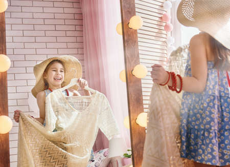 Happy girl dresses up at home. Funny lovely child is having fun in kids room.