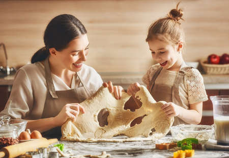 Happy loving family are preparing bakery together. Mother and child daughter girl are cooking cookies and having fun in the kitchen. Homemade food and little helper.の写真素材