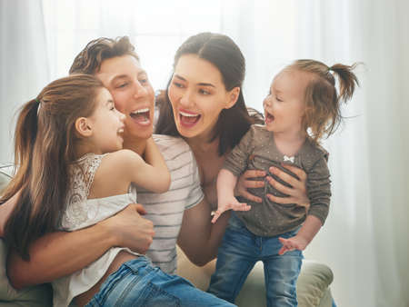 Happy father's day! Two children daughters with mother congratulate daddy. Mum, dad and girls laughing and hugging. Family holiday and togetherness.の写真素材