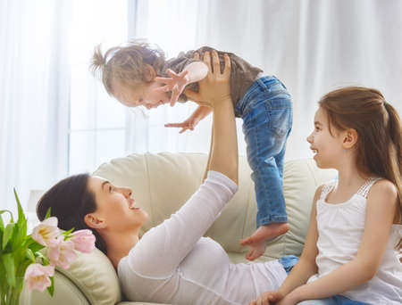 Happy mother's day! Mom and her daughters children girls are playing, smiling and hugging. Family holiday and togetherness.の写真素材