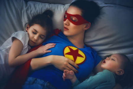 Adorable little children girls are napping in the bed with their mom. Quiet sleep under the...