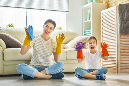 Happy family cleans the room. Mother and daughter do the cleaning in the house. A young woman and child girl are dusting. Cute little helper.の写真素材