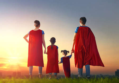Mother, father and their daughters are playing outdoors. Mommy, daddy and children girls in an Superhero's costumes. Concept of super family.の写真素材