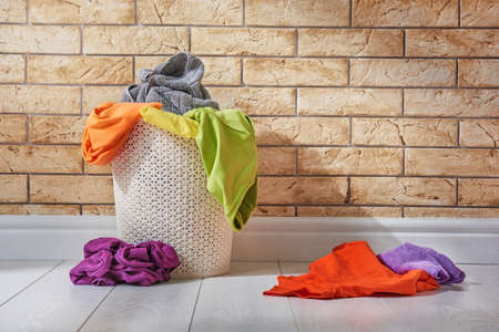 Basket with colored linen standing on the floor in the laundry room.の写真素材