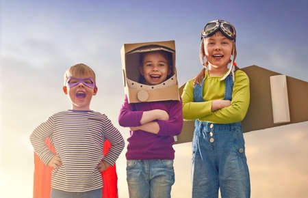 Children in astronaut, pilot and super hero costumes are laughing, playing and dreaming. Portrait of...