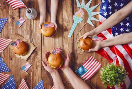 Patriotic holiday. Mother, father and child are doing burgers. Happy family are celebrate 4th of July. Top view with American flag in the room at home.の写真素材