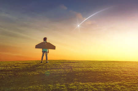 Little girl plays astronaut. Child on the background of sunset sky. Kid is looking at falling star...