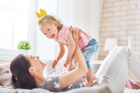 Happy loving family. Mother and her daughter child baby girl playing and hugging on the bed in bedroom.の写真素材