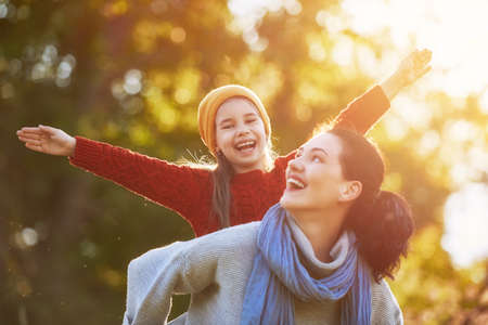 Happy family on autumn walk! Mother and daughter walking in the Park and enjoying the beautiful autumn nature.の写真素材