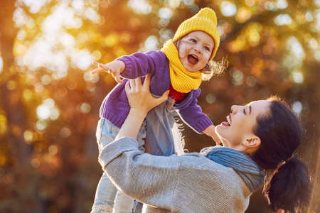 Happy family on autumn walk! Mother and daughter walking in the Park and enjoying the beautiful autumn nature.の写真素材