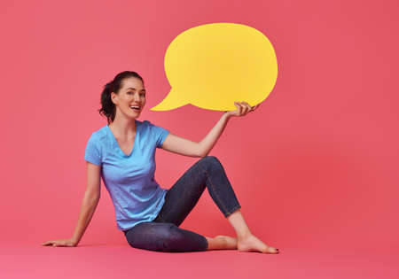 Beautiful young woman with cartoon speech on colorful background. Yellow, pink and blue colors.の写真素材