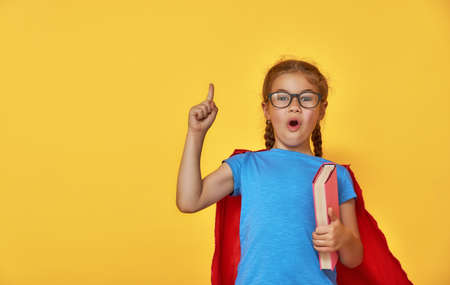 Little child plays superhero. Kid on the background of bright color wall. Education and success concept. Yellow, red and  blue.の写真素材