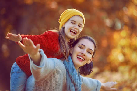 Happy family on autumn walk! Mother and daughter walking in the Park and enjoying the beautiful...