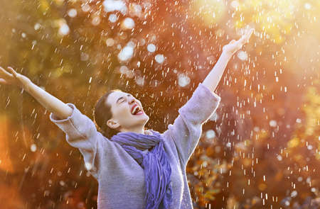 Happy beautiful young woman under the autumn shower. Girl is enjoying rainfall.の写真素材