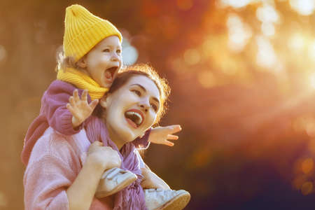Happy family on autumn walk! Mother and daughter walking in the Park and enjoying the beautiful autumn nature.の写真素材