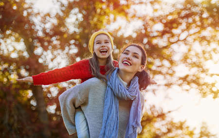Happy family on autumn walk! Mother and daughter walking in the Park and enjoying the beautiful autumn nature.の写真素材
