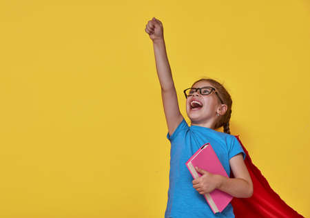 Little child plays superhero. Kid on the background of bright color wall. Education and success concept. Yellow, red and  blue.の写真素材