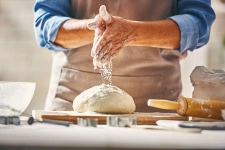 Close up view of baker is working. Homemade bread. Hands preparing dough on wooden table.