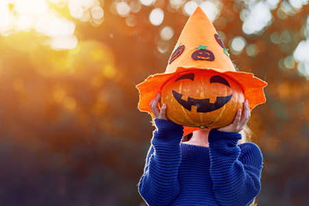 Happy Halloween! Cute little child with a pumpkin in the park.の写真素材