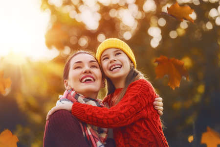Happy family on autumn walk! Mother and daughter walking in the Park and enjoying the beautiful autumn nature.の写真素材