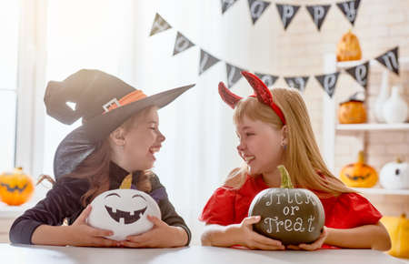 Cute little children girls with carving pumpkin. Happy family preparing for Halloween. Funny kids at home.の写真素材