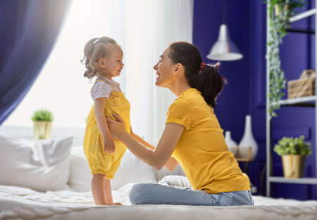 Mom and her daughter child girl are playing, smiling and hugging. Family holiday and togetherness.の写真素材
