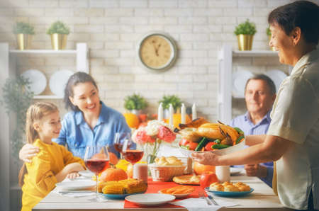 Happy Thanksgiving Day! Autumn feast. Family sitting at the table and celebrating holiday. Grandparents, parents and children. Traditional dinner.の写真素材