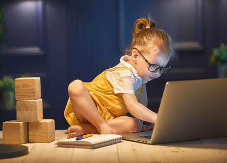 Cute baby girl working on a computer at home.