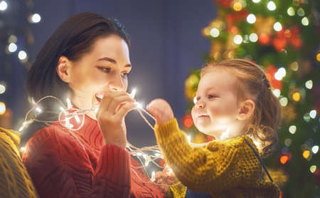 Merry Christmas and Happy Holiday! Mom and daughter near the tree at home.の写真素材