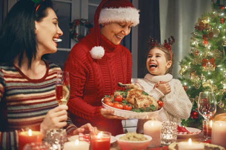 Merry Christmas! Happy family are having dinner at home. Celebration holiday and togetherness near tree.の写真素材