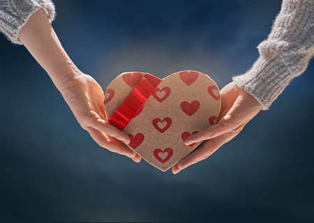 Couple on Valentines day. Red heart in woman and man hands.の写真素材