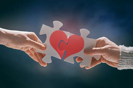 Man and woman put the red heart puzzle together. Concept of Valentine's day.