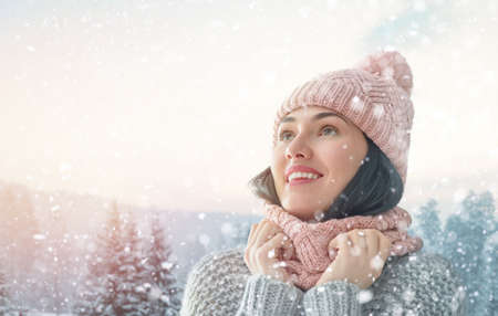 Happy young woman on snowy winter walk in nature. Concept of frost winter season.