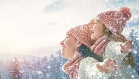 Happy loving family! Mother and child girl having fun, playing and laughing on snowy winter walk in nature. Frost winter season.の写真素材