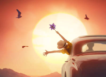 Toward adventure! Girl relaxing and enjoying road trip. Happy girl rides into the sunset in vintage...