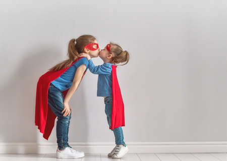 Little children is playing superhero. Kids on the background of bright wall. Girl power concept.