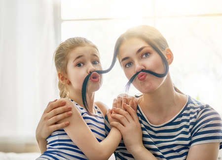 Mom and her child daughter are playing and having fun together. Beautiful funny girl and mother have...