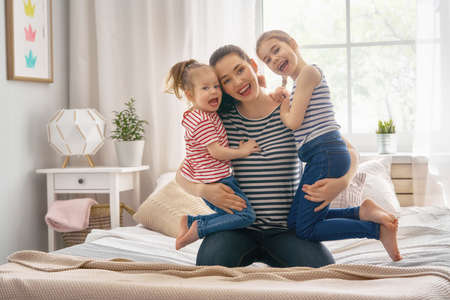 Happy loving family. Mother and  two her daughters children girls playing and hugging.の写真素材