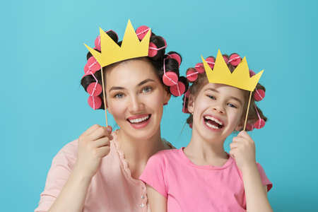Funny family! Mother and her child daughter with a paper accessories. Funny girls holding crown on stick.の写真素材
