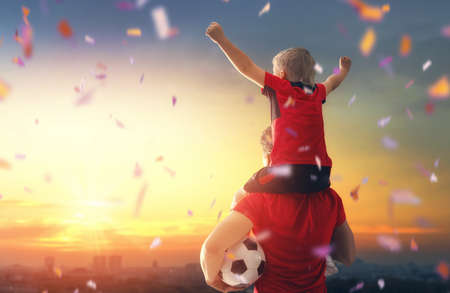Cute little child dreaming of becoming a soccer player. Boy with man playing football on sunset. Family sport.の写真素材