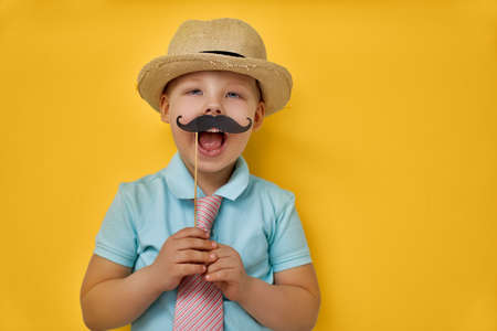 Funny time. Happy father's day! Boy playing and holding paper mustache on stick and pretending of daddy.の写真素材