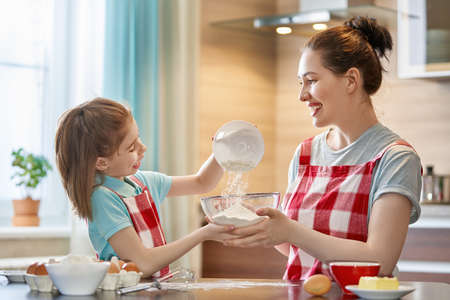 Happy loving family are preparing bakery together. Mother and child daughter girl are cooking...